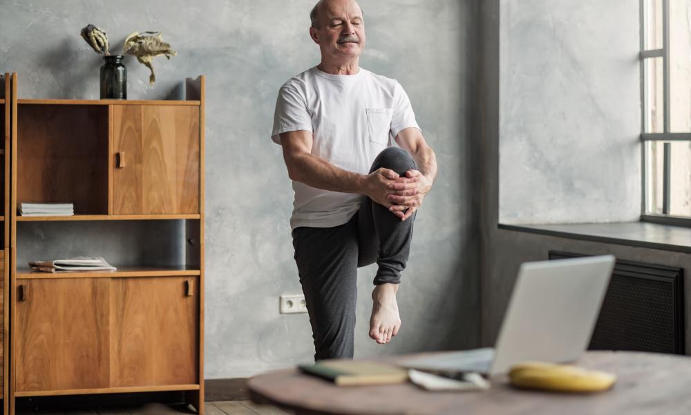 Older man performing exercises at home (online class)