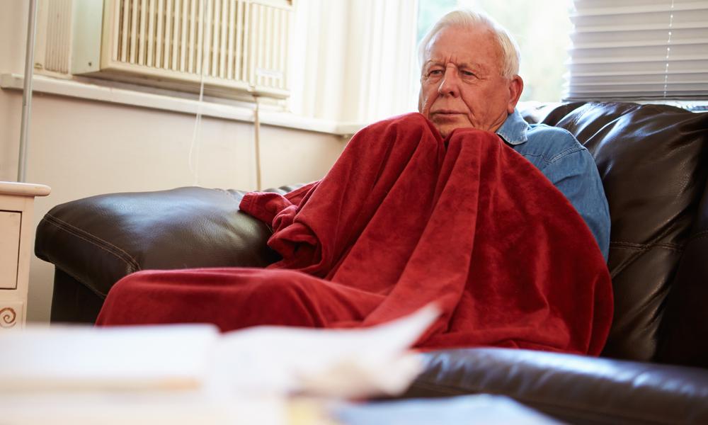 Older man on sofa in blanket 