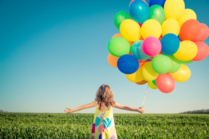 Child in field with balloons